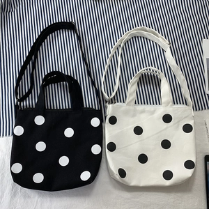 Detailed top view of black and white polka dot canvas crossbody bags with adjustable straps