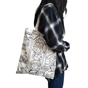 White canvas tote bag with black cartoon line drawings worn over a woman's shoulder
