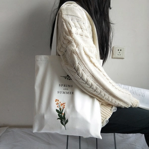 Detail of white canvas tote bag featuring orange flower prints and black text on front