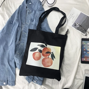 Detailed flat lay of a black canvas tote bag featuring realistic orange fruit prints
