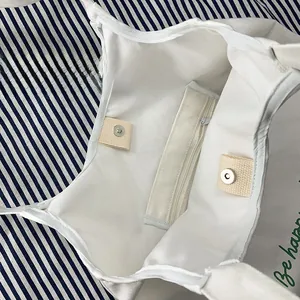 Detail of white canvas tote featuring internal zipper pocket and magnetic snap closures