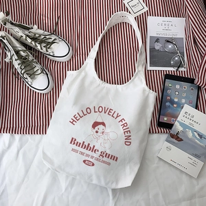 Detail of white canvas tote bag with red cartoon print on striped fabric background
