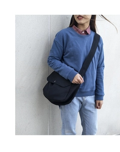 Detail of black canvas messenger bag featuring a wide strap and large capacity on a model