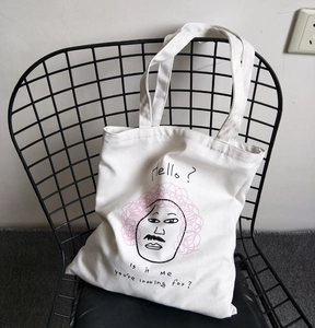 Borsa tote in tela minimalista con illustrazione e tipografia su una sedia in metallo