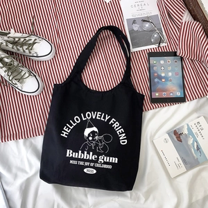 Black canvas tote bag with cartoon bubble gum boy print and casual styling props