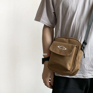 Minimalist brown canvas crossbody bag with white planet logo and adjustable black strap