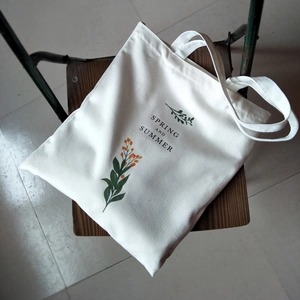 Detail of white canvas tote bag featuring floral print and Spring and Summer lettering