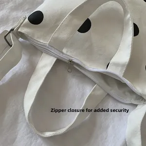 Close-up of secure zipper closure on cream canvas tote bag with black polka dots