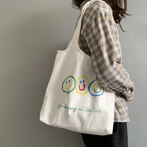 Minimalist white canvas tote bag with colorful smiley faces and Be Happy slogan