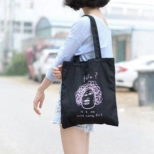 Dettaglio della borsa tote nera in tela con illustrazione rosa e scritta Hello