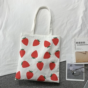 Close-up of strawberry print canvas tote bag with red fruit pattern on white fabric