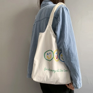 Detail of white canvas tote bag with colorful smiley faces and be happy all the time slogan