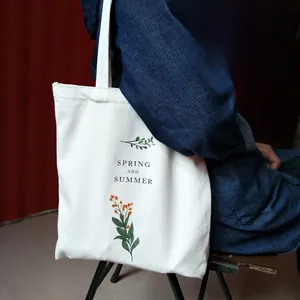 Detail of white canvas tote bag with spring summer floral print and lettering