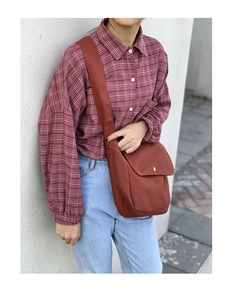 Detail view of a vintage dark red canvas crossbody bag with metal snap and wide strap