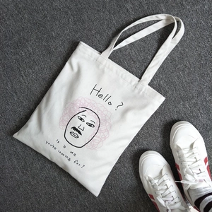 Dettaglio di una borsa tote in tela bianca con illustrazione artistica e scritta stampata