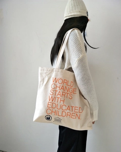Detail of canvas tote bag with orange slogan WORLD CHANGE STARTS WITH EDUCATED CHILDREN