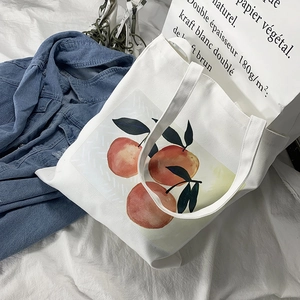 Versatile white canvas tote bag with fresh orange print on a lifestyle background