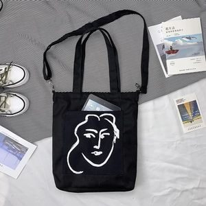 Détail du cabas en toile noire avec portrait minimaliste et espace pour tablette