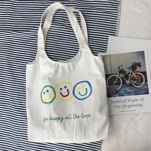 Detail of white canvas tote bag with colorful smile faces and Be Happy slogan print