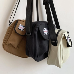 Three canvas crossbody messenger bags in khaki, black, and beige with adjustable straps