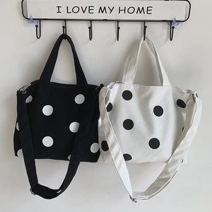 Polka dot canvas cross-body bag with top zipper and adjustable shoulder strap hanging
