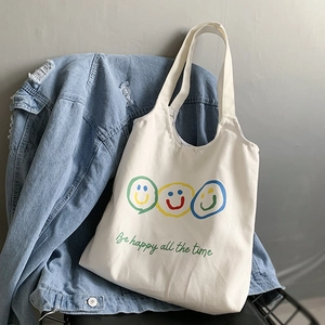 Detail of white canvas tote bag with colorful smileys and Be happy all the time text