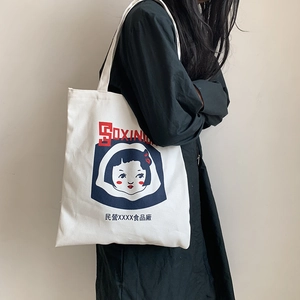 Detail of white canvas tote bag with retro print worn on shoulder over black dress