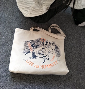 Detailed top view of a beige canvas tote bag with artistic bookstore illustration