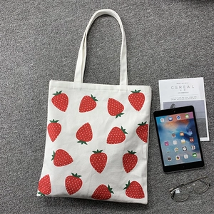 Detail of strawberry print canvas tote bag with magazine and tablet for size display