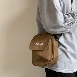 Close-up of brown canvas crossbody bag featuring white planet logo and adjustable strap