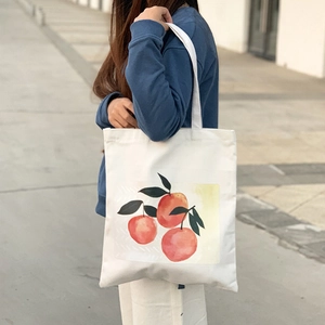 Close-up of durable white canvas tote bag featuring realistic orange fruit print details