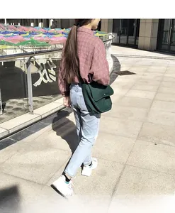 Detail shot of a dark green canvas messenger bag styled with a casual outdoor outfit