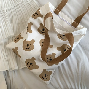 Vue de dessus d'un sac en toile blanc avec motifs ours brun et fermeture éclair