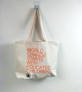 Detail of canvas tote bag with orange text World Change Starts With Educated Children