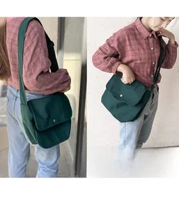 Detail of dark green canvas messenger bag showing adjustable strap and metal buckle closure