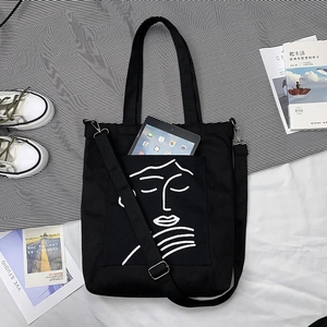 Détail du sac cabas en toile noire montrant l'espace pour tablette et le motif artistique