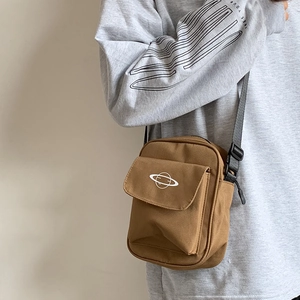 Detail shot of the khaki canvas crossbody bag featuring a white planet print and strap