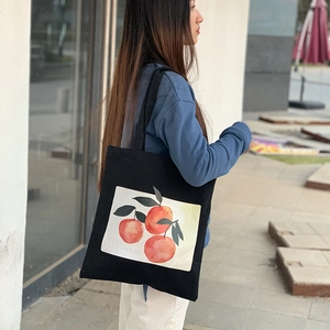 Detail shot of black canvas tote bag featuring artistic orange prints for daily use