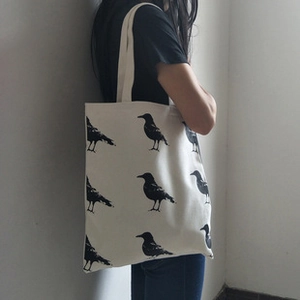 Détail d'un grand sac fourre-tout en toile blanc cassé avec motifs d'oiseaux noirs