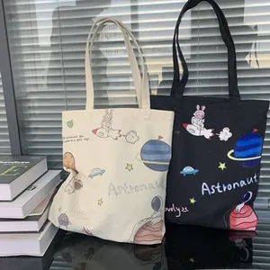 Détail de sacs cabas en toile avec imprimés d'astronautes en couleurs blanc et noir
