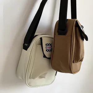 Detail view of canvas mini crossbody bags with adjustable straps in cream and brown