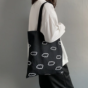 Photo lifestyle d'un sac cabas en toile noir avec motifs nuages blancs sur l'épaule