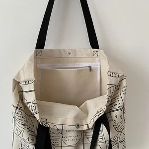 Detail view of canvas tote bag featuring magnetic buckle closure and inner zipper pocket