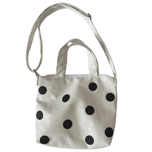 Polka dot canvas tote bag with adjustable shoulder strap and handles on white background
