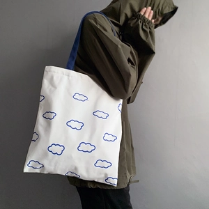 Détail du sac cabas en toile blanche avec motifs de nuages bleus et bandoulière en tissu