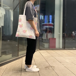 Detailed view of the pink peach print and 'fairy' text on a white canvas tote bag