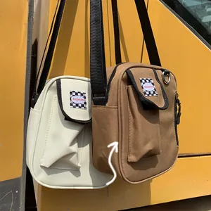 Detail of canvas crossbody bag with checkerboard tag and sturdy structured edge design