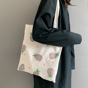 Détail du sac fourre-tout en toile à motif d'ananas porté par un mannequin de mode