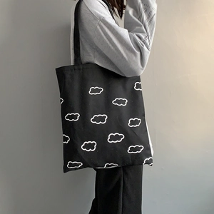 Détail du grand sac cabas en toile noire avec motif nuage porté par un mannequin