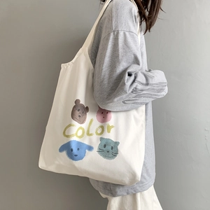 White canvas tote bag featuring colorful animal prints on a model in a casual setting